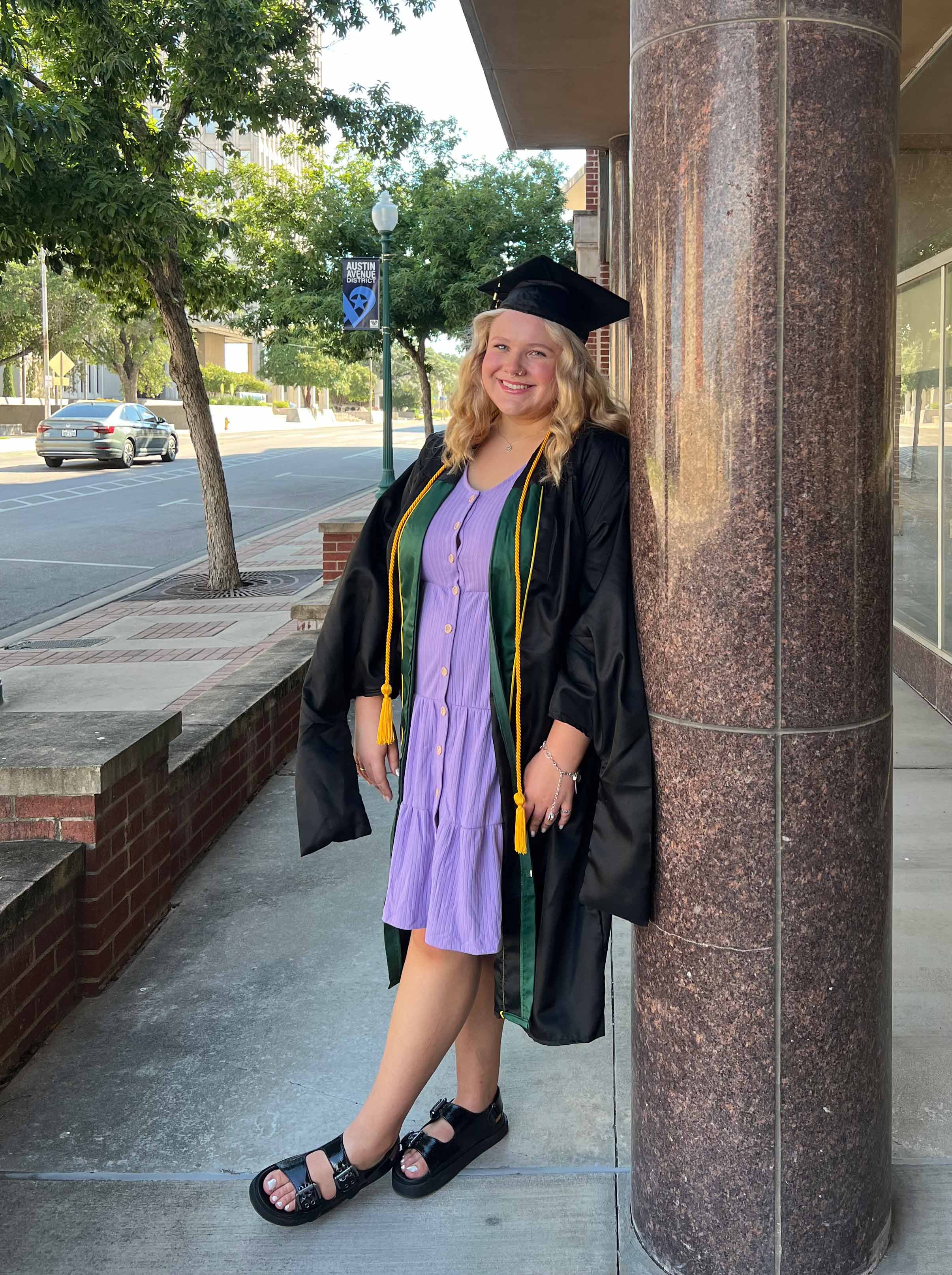 Miah Carter in graduation attire outside Garland School Downtown Waco Campus