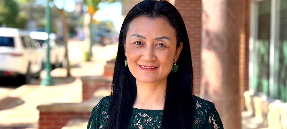 Dr. Ling Xu in front of the Garland School of Social Work in Waco, Texas.
