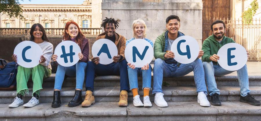 people sitting on a step each holding a letter spelling the word CHANGE