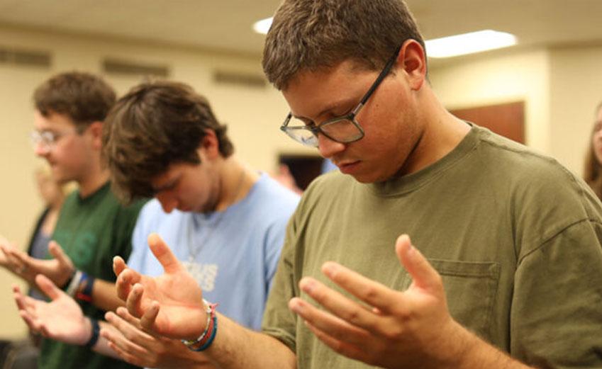 Students praying with hands open