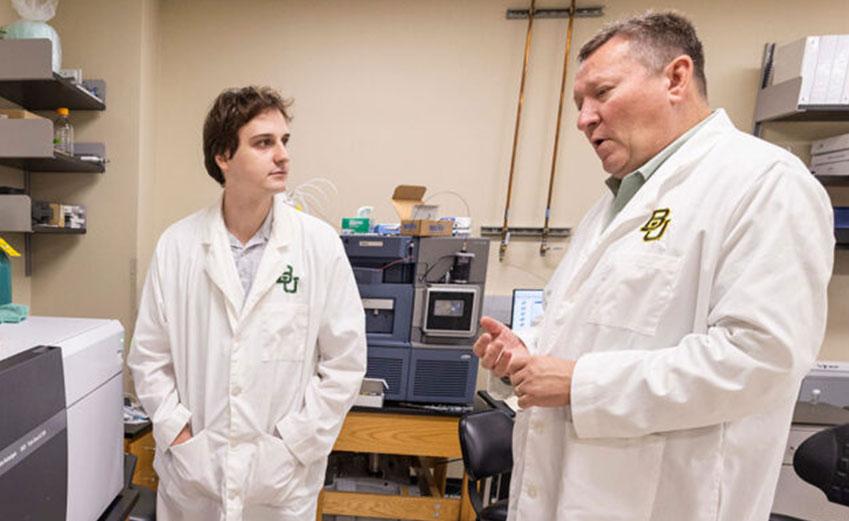 Student and professor in lab coats having a chat
