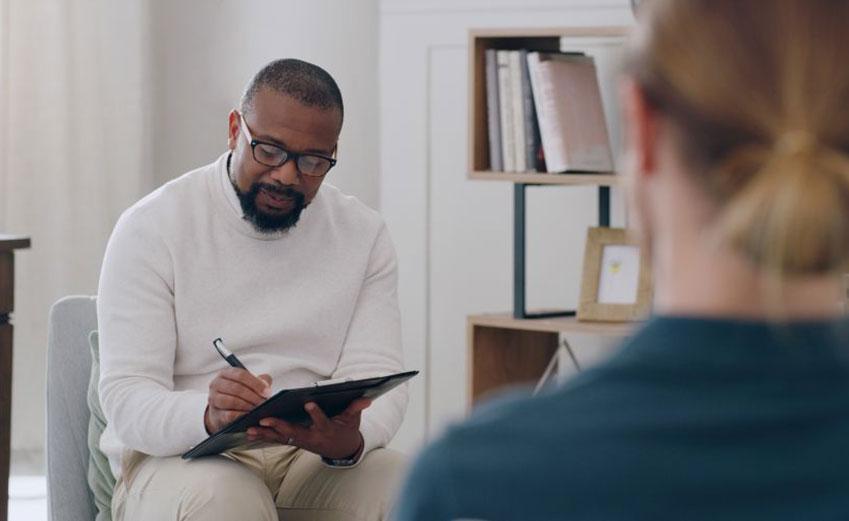 Counselor doing intake documentation with client in an office