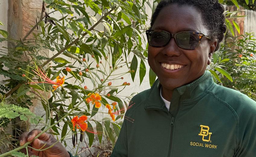 Dr. Stephanie Boddie holding a flowering plant during her trip to Ghana