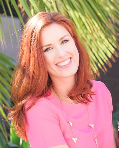 Ashley Hanna-Morgan portrait smiling with red hair and a pink shirt